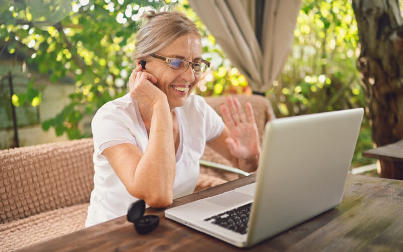 A woman sitting at a table, using a laptop while engaged in a phone conversation during a consultation meeting.
