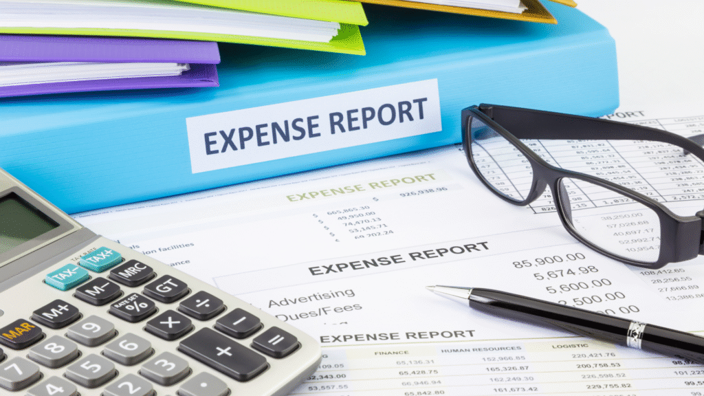 Business expense report documents with calculator, glasses, and pen on desk