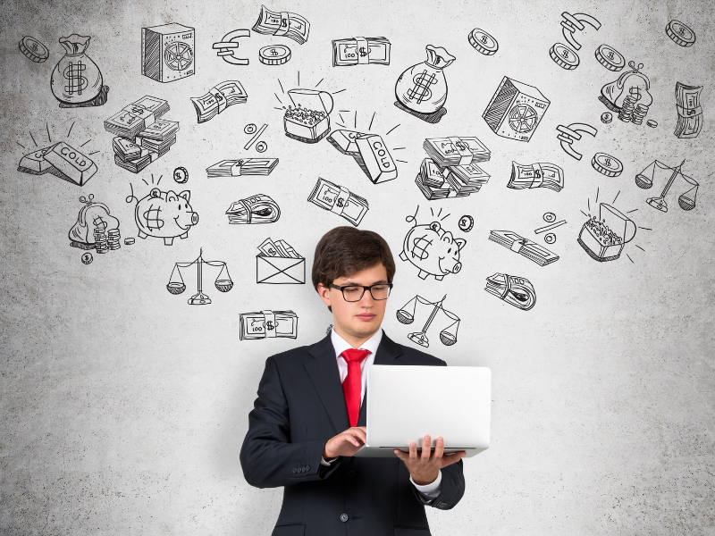 Young businessman using a laptop with financial and investment icons drawn on a wall, representing investing fundamentals and compounding growth.