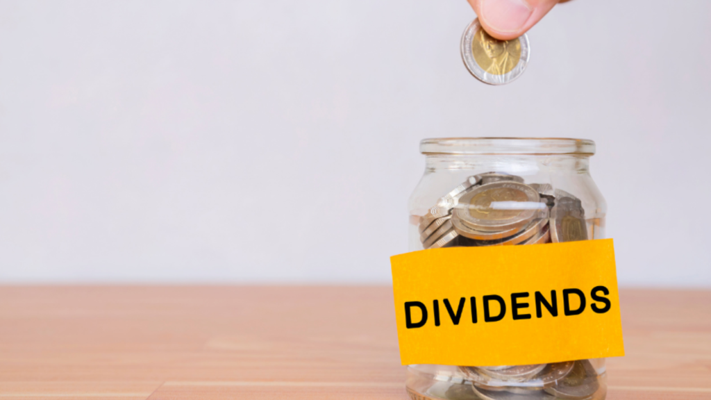Coins being added to a jar labeled “Dividends,” representing dividend-paying stocks with predictable quarterly income
