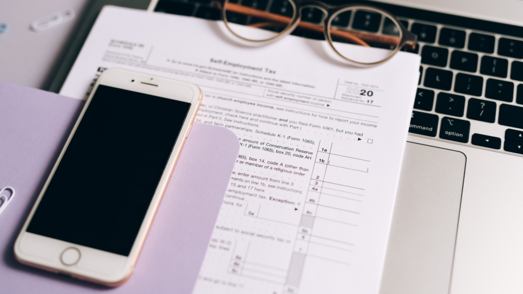 Retirement planning documents and tax paperwork on laptop desk