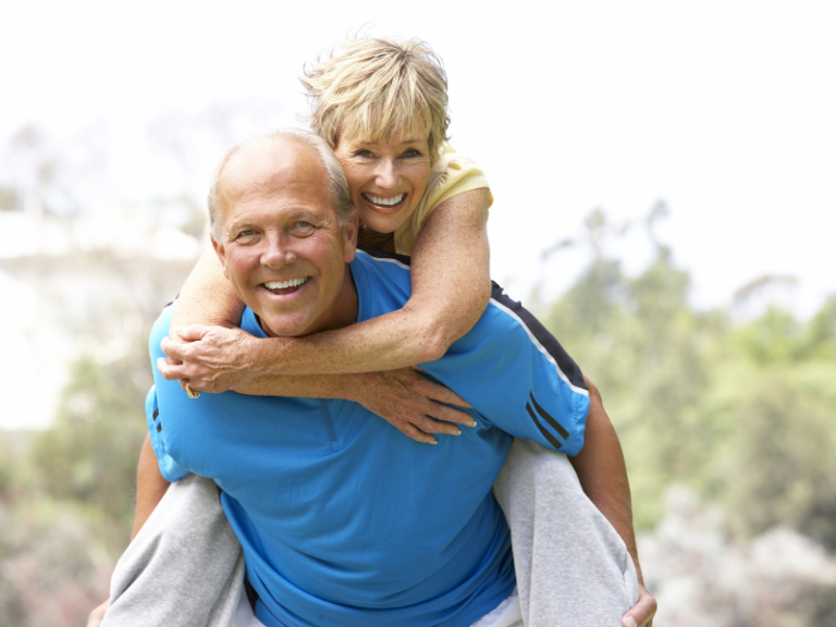 Smiling older couple in their 60s staying active outdoors, representing healthy retirement planning